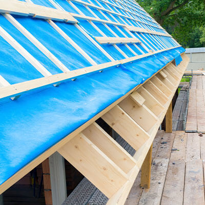 Bâche de couverture bleue en PVC sur une toiture en cours de construction